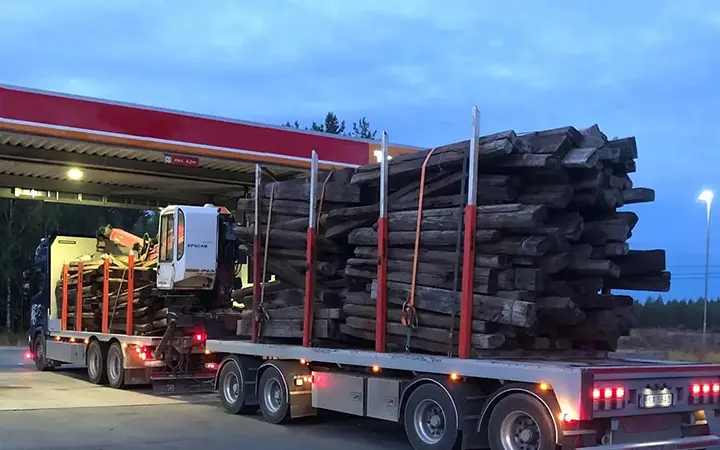 Jernbanesviller lastet på blå Scania kranbil